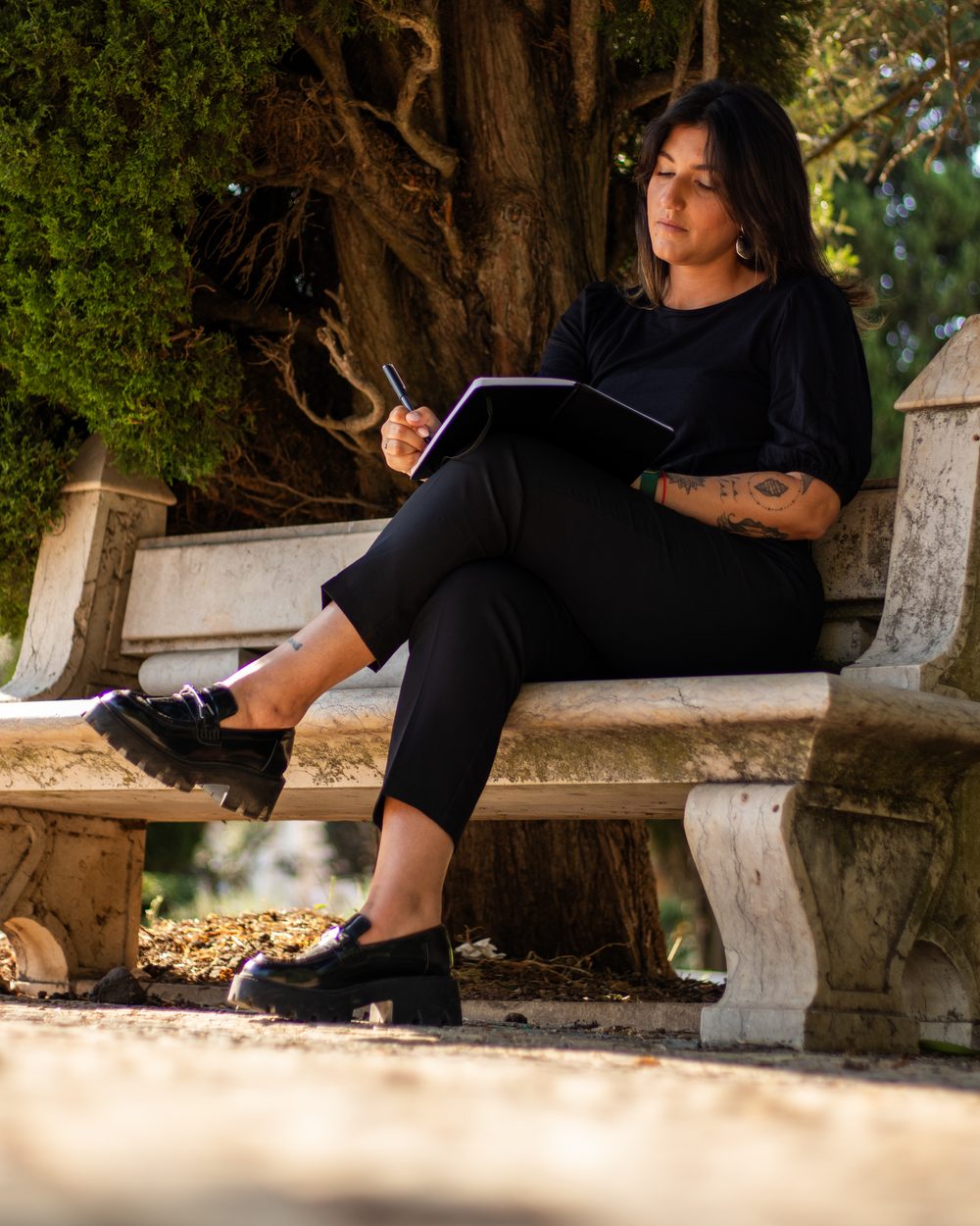 Carol Ferreira sentada, com caderno e caneta na mão